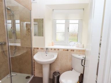 A bathroom with a shower enclosure a pedestal sink a toilet and a window at The Old Chapel in Crook