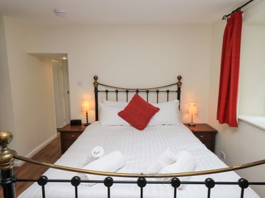 A bedroom with a double bed two bedside tables with lamps red curtains and rolled towels on the bed at The Old Chapel in Crook