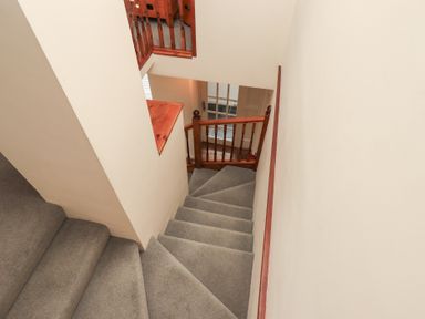A carpeted staircase with wooden handrails and beige walls at The Old Chapel in Crook