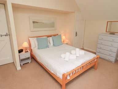 A bedroom with a wooden bed with white bedding and blue pillows two bedside tables with lamps and a chest of drawers with a mirror at The Old Chapel in Crook