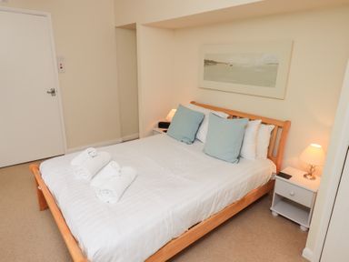 A bedroom with a bed with white linens and blue pillows a bedside table with a lamp and a painting above the bed at The Old Chapel in Crook