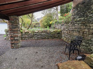 A covered outdoor area with stone walls and two black chairs at The Old Chapel in Crook