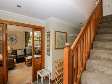 A hallway with a staircase and a clock at Middlerigg in Troutbeck