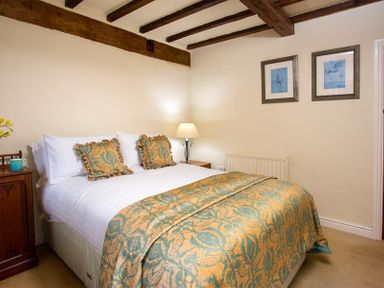 A bedroom with a double bed nightstands a table lamp and framed pictures on the wall at Bank Barn at Rusland in Grizedale