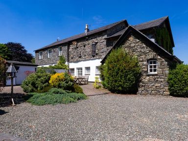 Stone house with gravel driveway and bushes in front at Bank Barn at Rusland in Grizedale