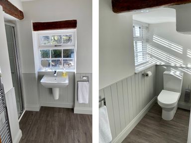 A bathroom with a sink under a window and a toilet near another window at Bank Barn at Rusland in Grizedale