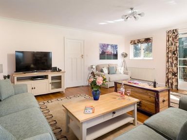 A living room with sofas a television and coffee tables at Juniper Cottage in Windermere