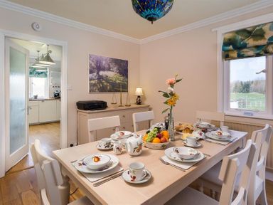 A dining room with a table set for six near a window at Juniper Cottage in Windermere
