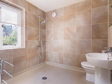 A bathroom with a shower area a toilet and a sink near a window at Juniper Cottage in Windermere