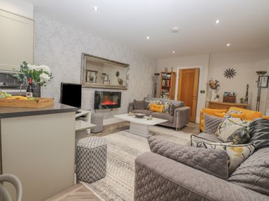 A living room with sofas pillows a coffee table a TV and a fireplace at Rossett Holme in Ambleside