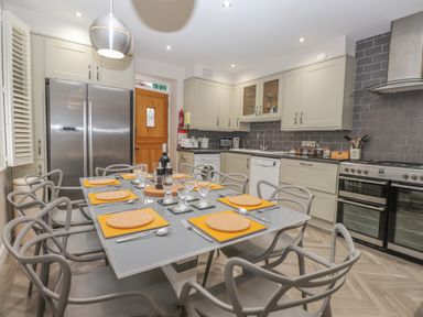A kitchen with a dining table set for eight people with plates glasses and cutlery at Rossett Holme Ambleside