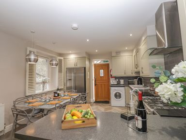 A kitchen with a dining table set with placemats and glasses beside a wooden door at Rossett Holme in Ambleside