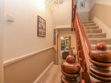 A carpeted staircase with a wooden banister and framed pictures on the wall at Rossett Holme in Ambleside