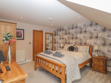 A bedroom with a wooden bed and bedside tables with lamps at Rossett Holme in Ambleside