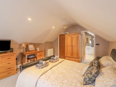 A bedroom with a bed towels wooden furniture a wardrobe a desk and a bathroom at Rossett Holme Ambleside