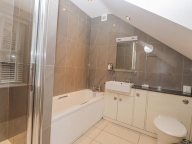 A bathroom with bathtub shower sink mirror toilet and cabinets at Rossett Holme in Ambleside