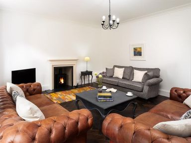 A living room with leather sofas a patterned fabric sofa a fireplace and a coffee table at Ben House in Grasmere