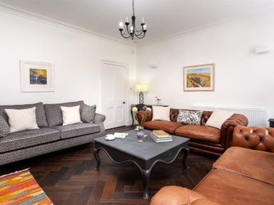 A living room with sofas coffee table lamp and paintings at Ben House in Grasmere