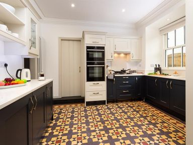 A kitchen with black and white cabinets patterned tiled floor and various kitchen appliances at Ben House in Grasmere