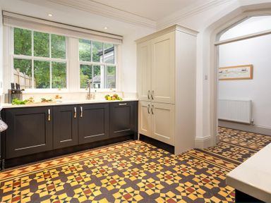 A kitchen with patterned tile floor black and white cabinets and large windows at Ben House in Grasmere