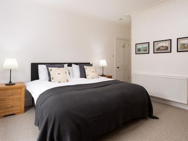 A bedroom with a large bed bedside tables lamps and framed pictures on the wall at Ben House in Grasmere