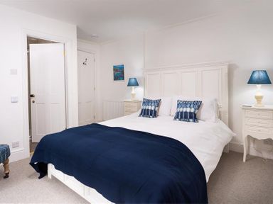 A bedroom with a white bed and blue bedding beside two nightstands with lamps at Ben House in Grasmere