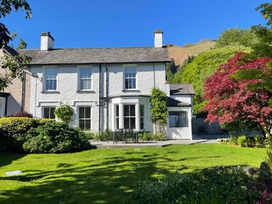 A white two story house with a garden and outdoor furniture at Ben House in Grasmere