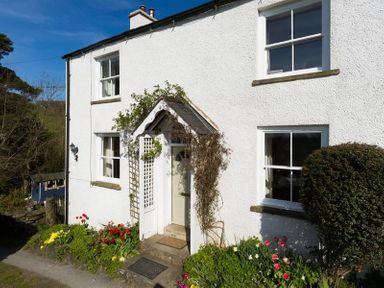 The exterior of a white house with a garden and flowers by the entrance at Birchmill Cottage in Crook