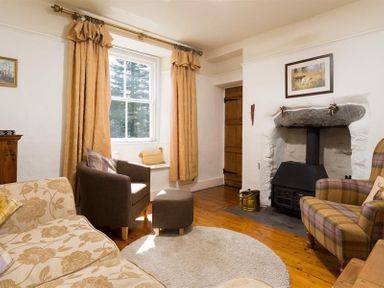 A living room with a fireplace armchairs a sofa and curtains at Birchmill Cottage in Crook