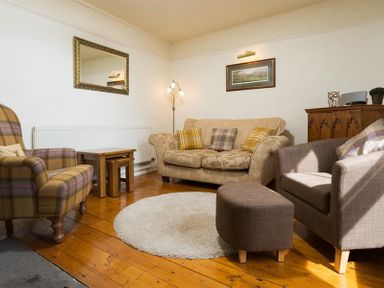 A living room with armchairs a sofa a wooden floor a round rug and a wooden cabinet at Birchmill Cottage in Crook