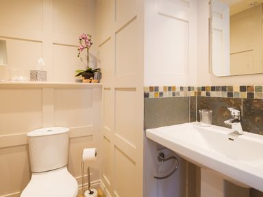 A bathroom with a toilet and sink with tiled backsplash at Birchmill Cottage in Crook