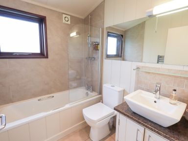 A bathroom with a bathtub, toilet, sink, and shower at Thie Loghey in Hawkshead