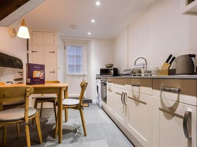 A kitchen with a wooden table and chairs and cabinets with appliances at Lettera in Ambleside