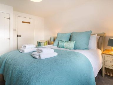 A bedroom with a bed with blue bedding and pillows and two bedside tables with lamps at Lettera Ambleside