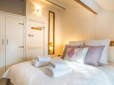 A bedroom with a bed with folded towels and pillows next to a door and a wall mirror at Lettera Ambleside