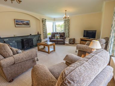 A living room with sofas a coffee table a fireplace and a television at Laal Field House in Keswick