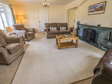 A living room with armchairs a sofa a wooden coffee table and a fireplace at Laal Field House in Keswick