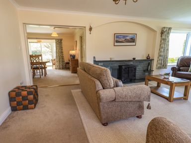 A living room with a sofa armchair coffee table fireplace and a dining table in the background at Laal Field House in Keswick