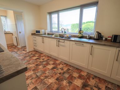 A kitchen with white cabinets and a tiled floor at Laal Field House in Keswick