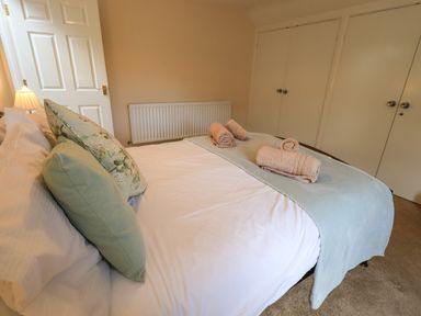 A bedroom with a bed with pillows and rolled towels and a lamp on a bedside table at Laal Field House in Keswick