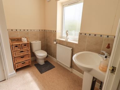 A bathroom with a toilet a sink a wicker storage unit and a window with blinds at Laal Field House Keswick