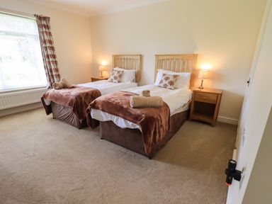 A bedroom with two single beds bedside tables lamps and a window at Laal Field House in Keswick