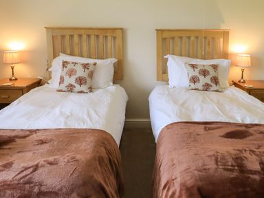 A bedroom with two single beds bedside tables and lamps at Laal Field House in Keswick