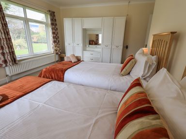 A bedroom with two single beds white wardrobes and a large window at Laal Field House in Keswick