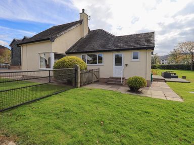 A house with a fenced lawn and patio in front surrounded by bushes at Laal Field House in Keswick