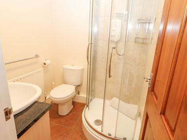 A bathroom with a toilet sink and curved glass shower at Goswick Hall in Bowland Bridge