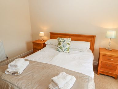 A bedroom with a wooden bed and two bedside tables with lamps at Goswick Hall in Bowland Bridge