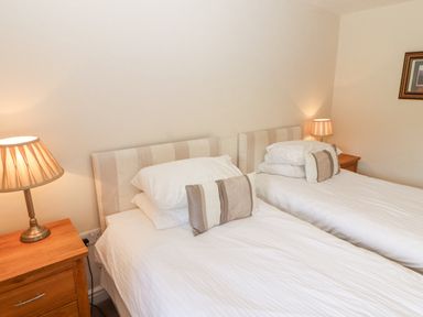 A bedroom with two single beds bedside tables and lamps at Goswick Hall in Bowland Bridge