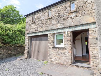 Stone building exterior with a garage door and open entrance showing hallway at Goswick Hall in Bowland Bridge