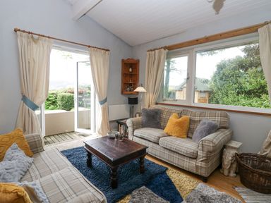 A living room with two plaid sofas and a wooden coffee table next to large windows and a sliding glass door at Lake Lodge in Bowness-On-Windermere